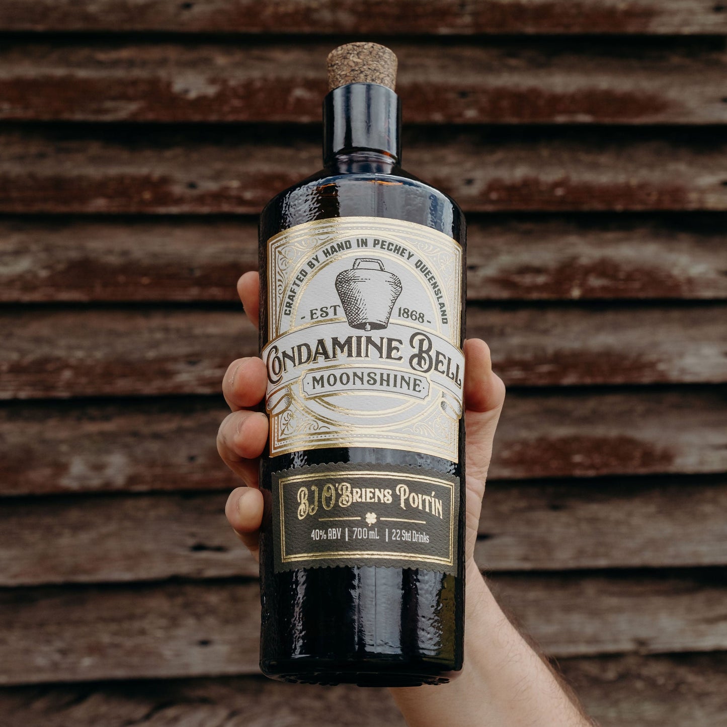 Bottle of Andamine Bell Moonshine held against a wooden background