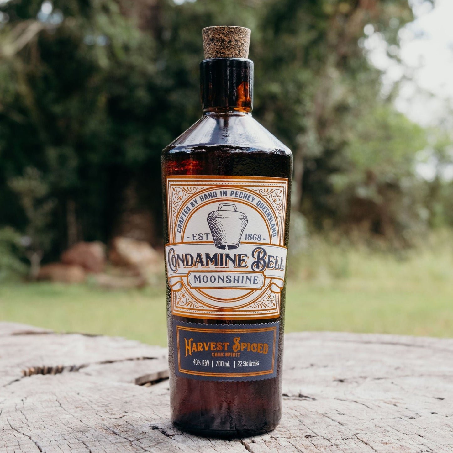 Bottle of Moonshine on a wooden log with trees in the background