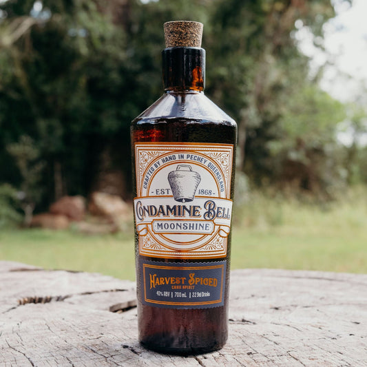 Bottle of Moonshine on a wooden log with trees in the background